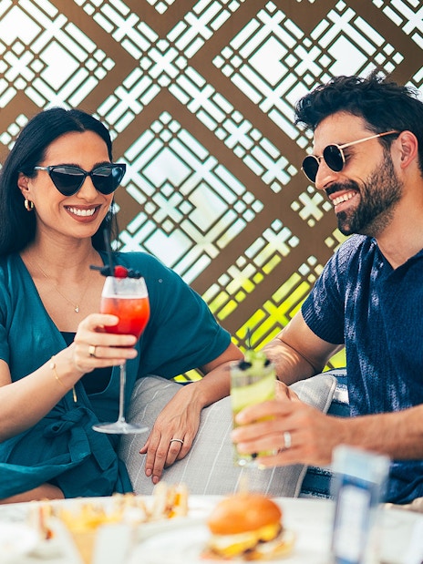 Two people enjoying cocktails together with a decorative background