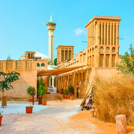 Traditional architectural courtyard with sand-colored buildings and a clear blue sky.
