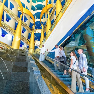 People walking on a escalator in a modern building with colorful ceiling design.