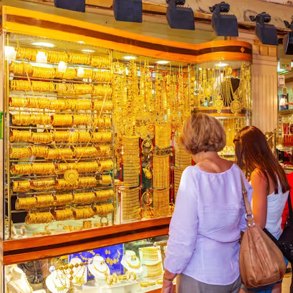People looking at gold jewelry display in a store