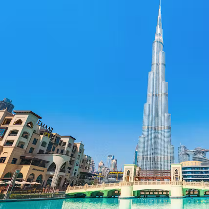 The Burj Khalifa in Dubai with surrounding buildings and a clear blue sky.